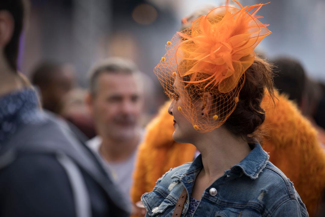 Woman with an orange fascinator in a festival crowd