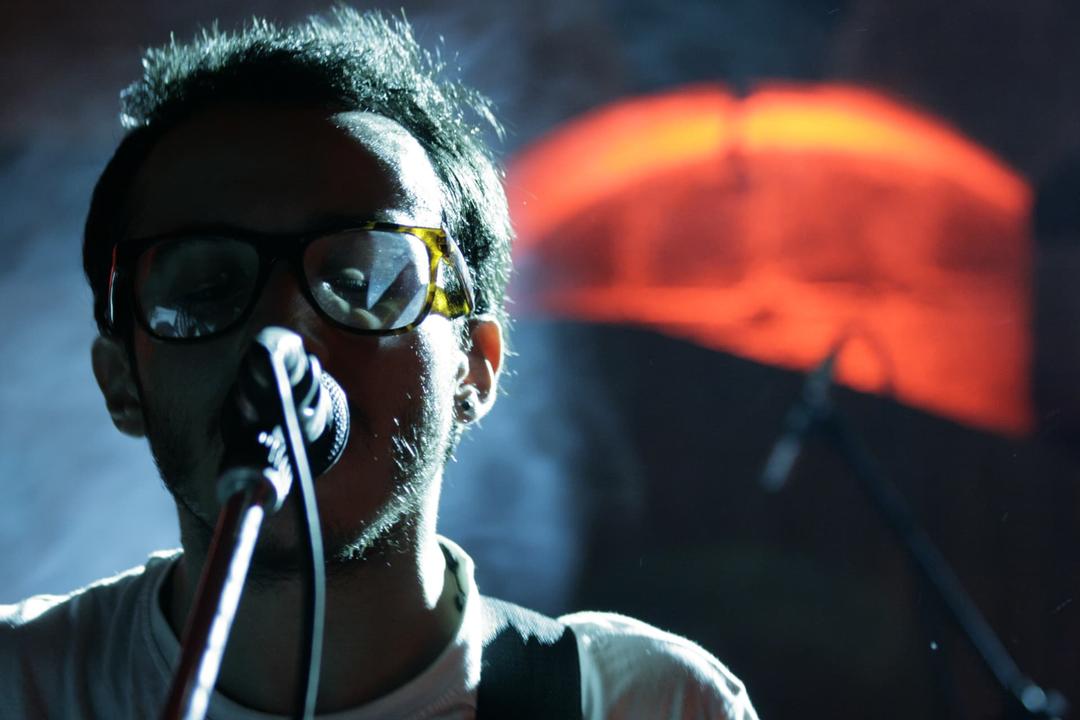 Musician singing into a microphone under atmospheric stage lighting